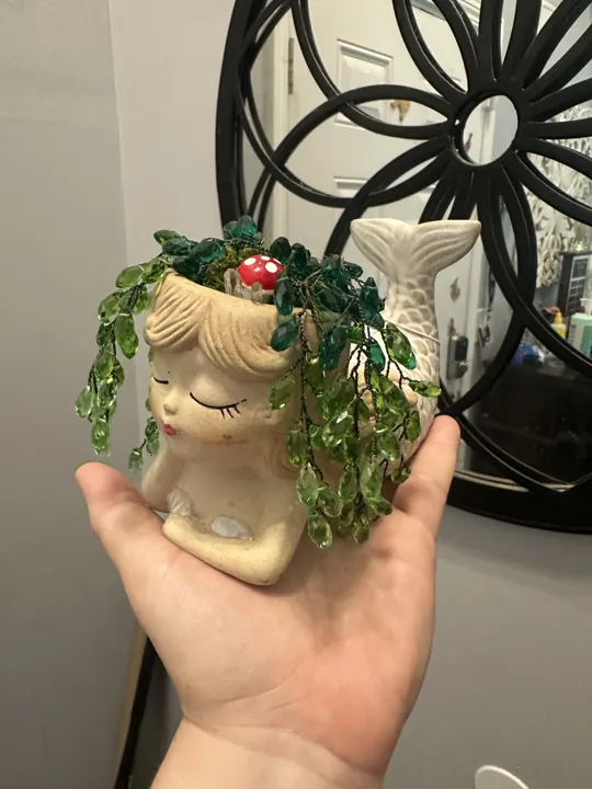 Trailing beaded greenery spilling from a face-shaped planter
